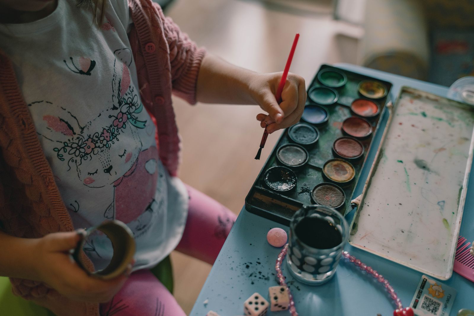 A child painting with watercolours at a little blue table