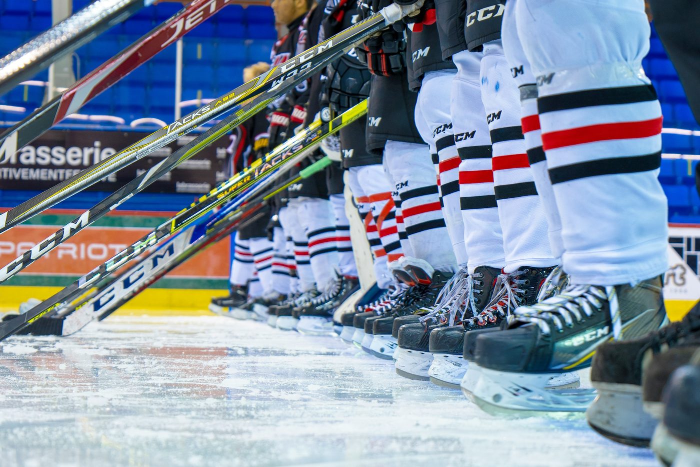 A hockey team lined up at the blue line, skates and sticks in a row